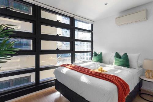 a bedroom with a bed and a large window at Central 2BR Apt by Melbourne Central City Views in Melbourne
