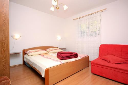 a bedroom with a bed and a red chair at Apartment Rogacic 2460a in Vis