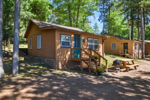 a tiny house in the woods with a picnic table and a grill at Whispering Waters Bayview Resort Cabin 4 in Saint Germain