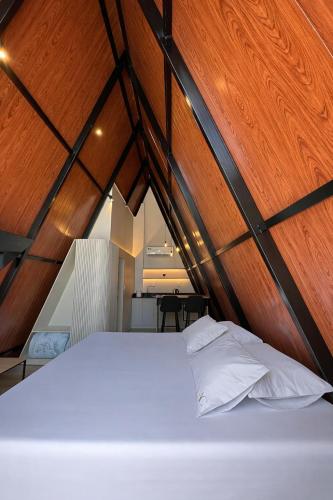 a white bed in a room with wooden walls at Âmbar Chalés in Ametista do Sul