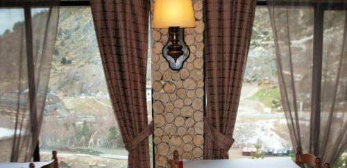 a room with a window with curtains and a lamp at Hotel Roc de St Miquel & Apartment in Soldeu