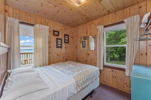 a bedroom with a bed and two windows at TB5 Thunder Bay Resort Cabin5 in Phelps