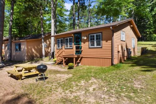 a cabin in the woods with a grill and a bbq at Bayview Resort Waters Edge Cabin 2 in Saint Germain