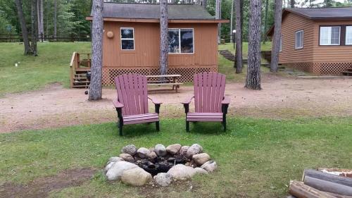 two chairs and a table and a fire pit in a yard at Bayview Resort Sandy Shores Cabin 3 in Saint Germain