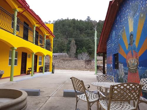 a table and chairs in front of a building with a mural at Hotel Ecológico Temazcal in Creel