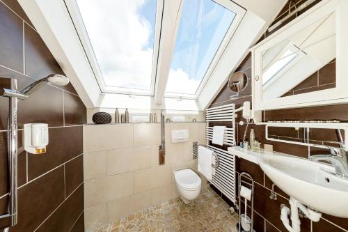a bathroom with a sink and a toilet and a skylight at Familien- und Wellnesshotel "Viktoria" in Oberstdorf