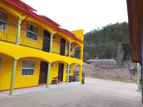 a yellow building with a balcony on the side of it at Hotel Ecológico Temazcal in Creel