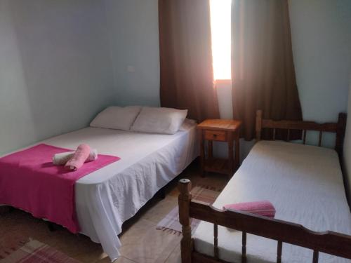a bedroom with two beds and a stuffed animal on a pink blanket at chalé 8a 4 in Cunha
