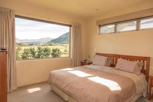 a bedroom with a bed and a large window at Arrowtown Dress Circle in Arrowtown