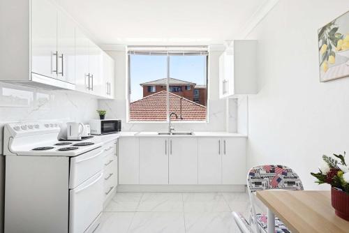 a white kitchen with a sink and a window at Convenient Single Stay in Vibrant Cabramatta - Shared Bathroom in Cabramatta