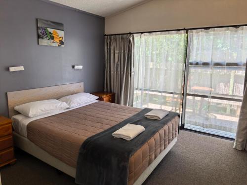 a bedroom with a bed and a large window at Judges Pool Motel Turangi in Turangi