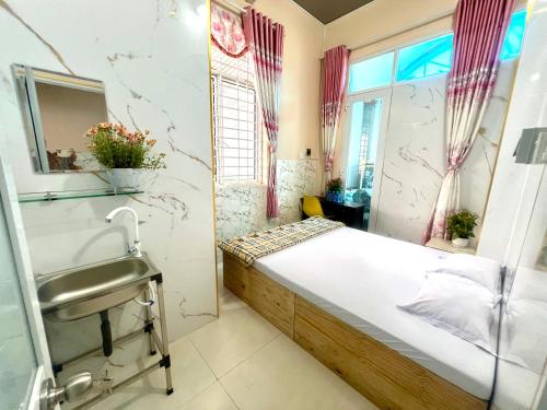 a bedroom with a bed and a sink and a window at La Mera Homestay in Ben Tre