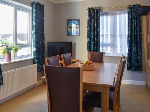 a dining room with a table and chairs and windows at Sea View Cottage in Rhos-on-Sea