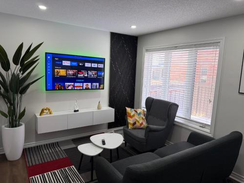 a living room with a couch and a tv on a wall at Cozy Private Two-Level Suite In Brampton With Separate Entrance And Living Area on Main Floor in Brampton