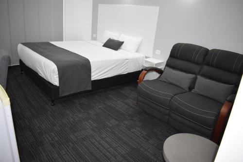 a bedroom with a bed and a couch at Riviana Motel in Deniliquin