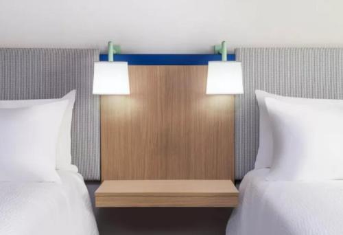 a bedroom with two beds and two lights on a headboard at Garner Hotel Albuquerque Airport by IHG in Albuquerque
