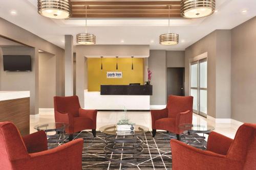 a meeting room with red chairs and a table at Park Inn by Radisson Brampton, ON in Brampton