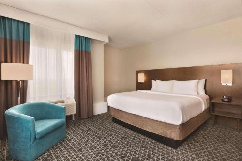 a hotel room with a bed and a blue chair at Park Inn by Radisson Brampton, ON in Brampton