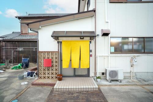 a building with a yellow and yellow front door at Oyadoya Nagakute 一軒貸切 ジブリ直結駅徒歩1分 BBQ常設 駐車場3台 in Owariasahi