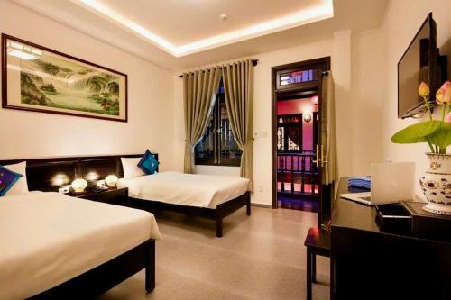 a hotel room with two beds and a desk at La Mera Homestay in Ben Tre
