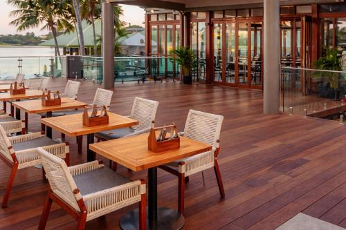 a restaurant with wooden tables and chairs on a deck at Large Family Sized Unit with Watersports, Maroochy River, Lagoon, and Beach Access in Twin Waters