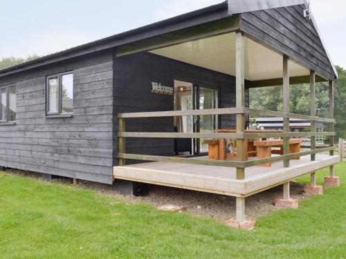 a black house with a porch and a deck at Larch Lodge in Bentley