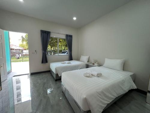 a bedroom with two beds and a window at Karon Little House in Karon Beach