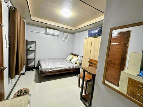a small room with a bed and a table at IBM Homestay in Butuan