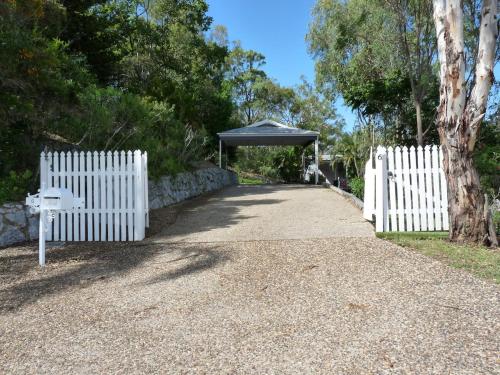 a white fence with a gazebo next to a gravel road at Bushland Breeze - Self Contained Unit in Gladstone