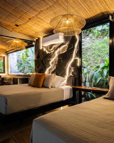 two beds in a room with a stone wall at Jungla EcoLuxury Resort in Villeta