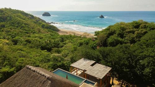 a view of a beach with a house and the ocean at Casa Yute Boutique Hotel Playa Aragon in San Agustinillo