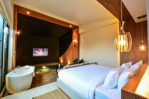 a bedroom with a tub and a bed and a sink at K2Green Hotel in Kanchanaburi City