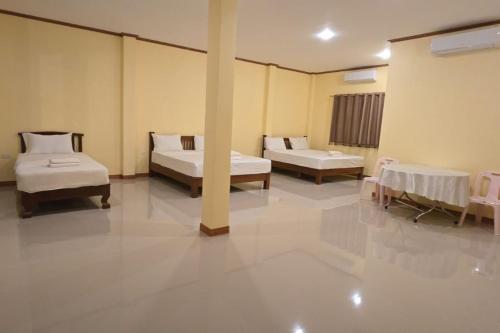 a room with two beds and two tables at Nongsak Riverside Guesthouse & Nongsak Guesthouse in Ban Khon