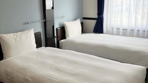 two beds sitting next to each other in a room at Toyoko Inn Shin takaoka eki Shinkansen Minami guchi in Takaoka