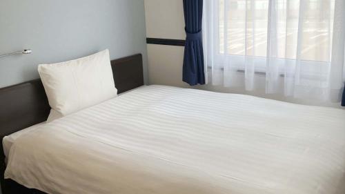a white bed with a window in a bedroom at Toyoko Inn Shin takaoka eki Shinkansen Minami guchi in Takaoka