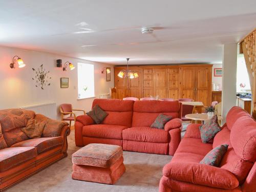 a living room with red couches and a table at The Barn in Waberthwaite
