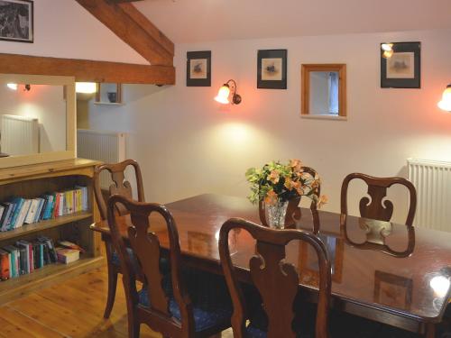 a dining room table with a vase of flowers on it at The Barn in Waberthwaite