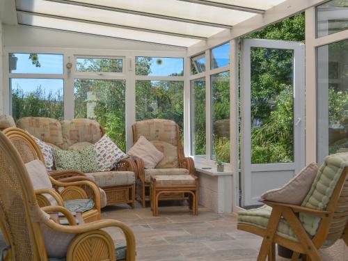 a screened in porch with rocking chairs and windows at Cherry Garth in Goathland