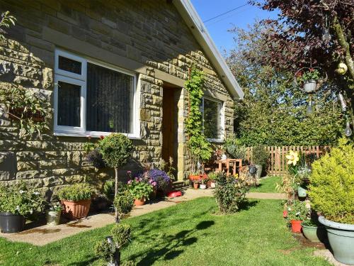 a stone house with a yard with potted plants at Mystified Bungalow in West Burton