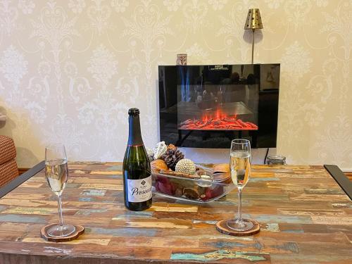 a bottle of wine and two glasses on a table with a fireplace at Mystified Bungalow in West Burton