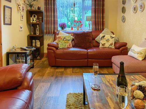 a living room with brown leather couches and a table at Mystified Bungalow in West Burton