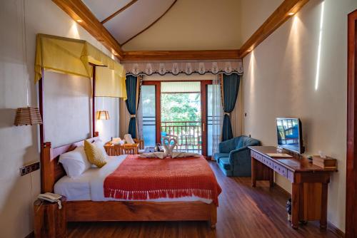 a bedroom with a bed and a desk and a television at Vangvieng Lina hotel in Vang Vieng