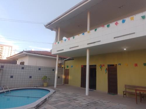 a house with a swimming pool in front of a building at Melos hospedagem jp in João Pessoa