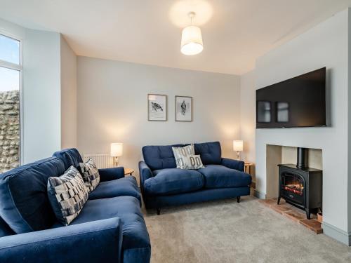 a living room with two blue couches and a fireplace at Stones Throw Cottage in Sheringham
