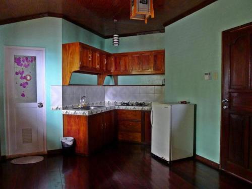 una cucina con mobili in legno e un frigorifero bianco di La Salangane Caalan Beach Villa a El Nido