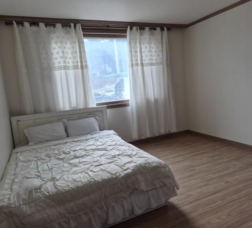a bedroom with a bed in front of a window at Hwacheon Ujune Minbak in Hwach'ŏn