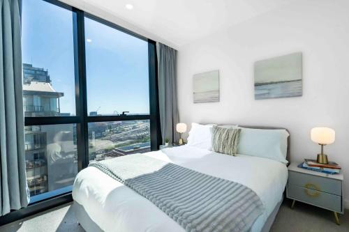 a bedroom with a white bed and large windows at Boutique 1B2B HighRise Condo in CBD in Melbourne