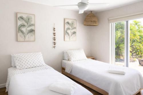 two beds in a room with a window at Large Family Sized Unit with Watersports, Maroochy River, Lagoon, and Beach Access in Twin Waters