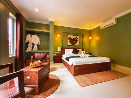 a bedroom with a king sized bed and a table at Siem Reap ABACUS Hotel in Siem Reap