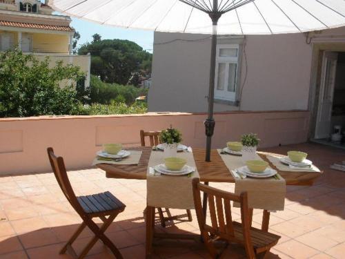 stół z krzesłami i parasol na patio w obiekcie Villa Charme w mieście Estoril
